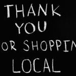 A chalkboard with handwritten message thanking for supporting local businesses.