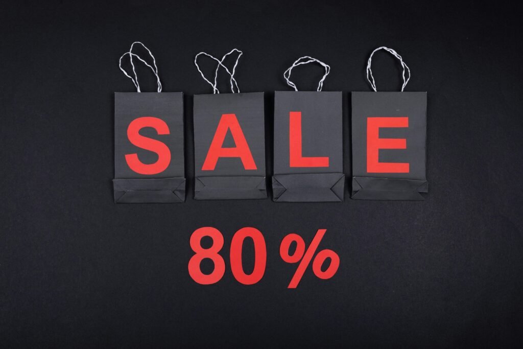 Highlighting a sale with 80% discount using black shopping bags and bold red text.