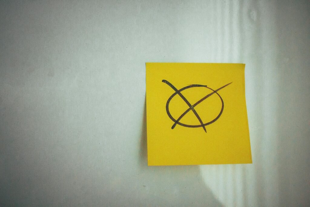 A yellow sticky note with a large black crossed circle on a white surface, perfect for business or office themes.