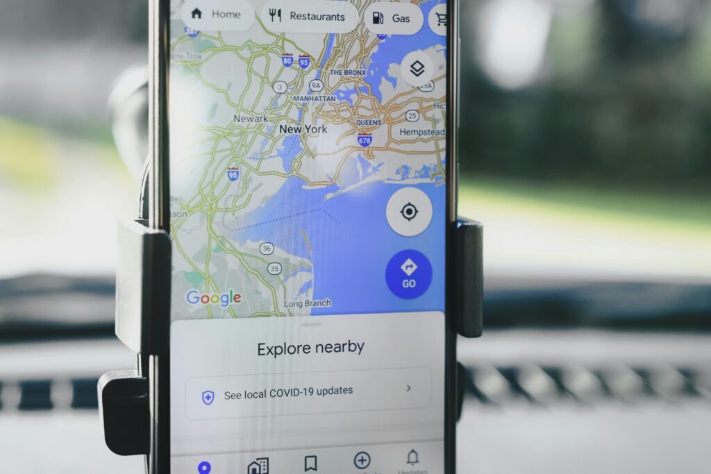 A smartphone displaying GPS map of New York City secured in a car mount during daylight. Ficha de google business profile
